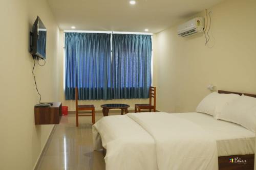 a bedroom with a bed and a tv and a window at GLANCY'S GUEST HOUSE in Haripād