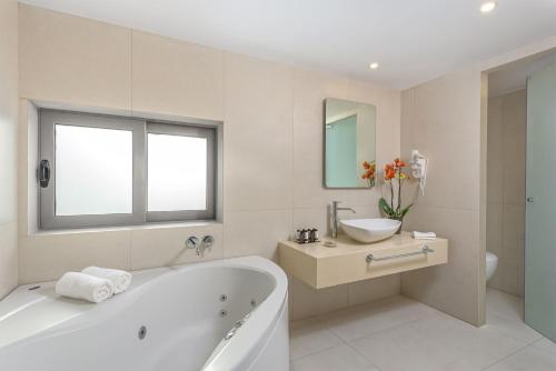 a white bathroom with a tub and a sink at The Ixian Grand & All Suites - Adults Only Hotel in Ixia