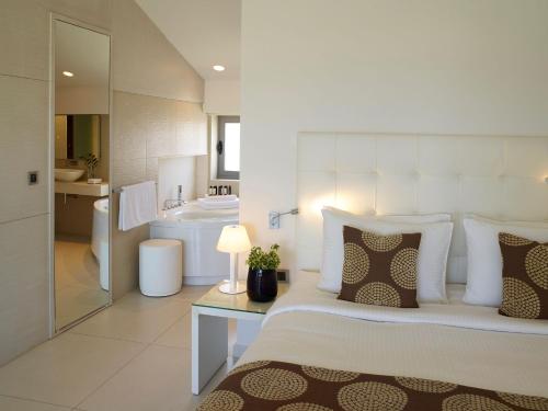 a white bedroom with a bed and a bathroom at The Ixian Grand & All Suites - Adults Only Hotel in Ixia