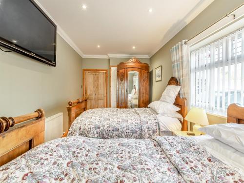 a bedroom with two beds and a flat screen tv at The Old Farmhouse in Ancroft