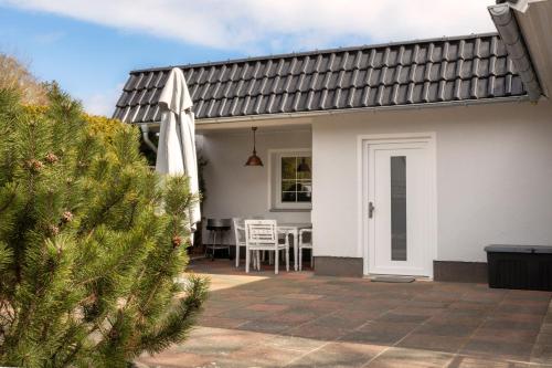 een wit huis met een patio met een tafel en stoelen bij Ferienhaus Hus Oetti in Ostseebad Sellin