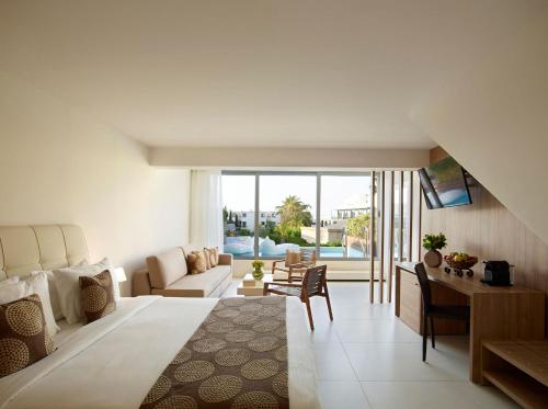 a bedroom with a large bed and a living room at The Ixian Grand & All Suites - Adults Only Hotel in Ixia