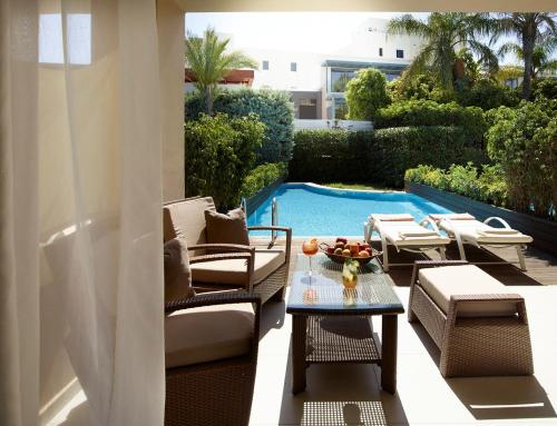 a patio with chairs and a table and a swimming pool at The Ixian Grand & All Suites - Adults Only Hotel in Ixia