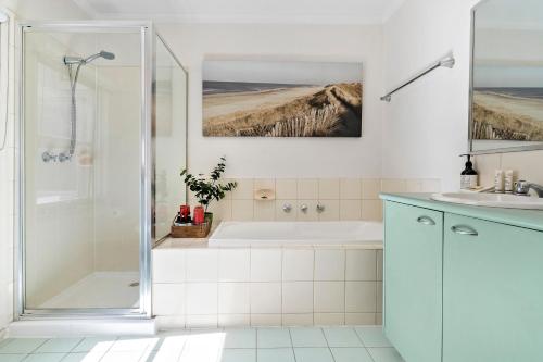 a bathroom with a shower and a tub and a sink at Kensington Escape - Balcony, BBQ and Parking in Melbourne