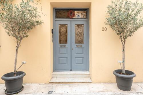 two trees in pots in front of a door at Athenian Niche in Plaka Villa by Athenian Homes in Athens