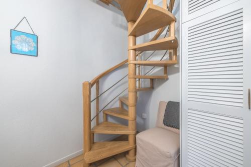 a wooden spiral staircase in a room with a chair at Athenian Niche in Plaka Villa by Athenian Homes in Athens