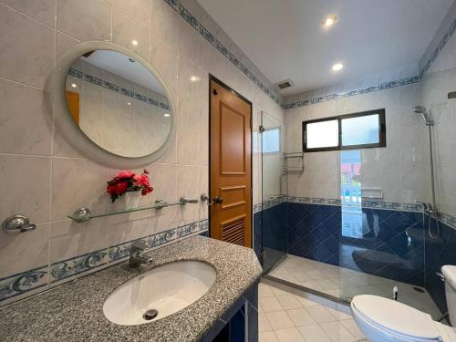 La salle de bains est pourvue d'un lavabo, d'un miroir et de toilettes. dans l'établissement Resort 2-3BR Huge Pool, BBQ, 300m-Beach, 5 mins to Walking Street, à Pattaya (sud)