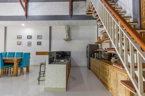 a kitchen and dining room with a staircase and blue chairs at Surf Retreat Villa Sari Bali in Pulukan