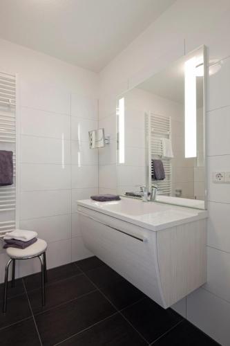 a white bathroom with a sink and a mirror at Exquisit 3 in Norderney