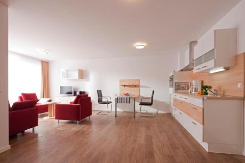 een keuken en een woonkamer met rode stoelen en een tafel bij Exquisit 3 in Norderney