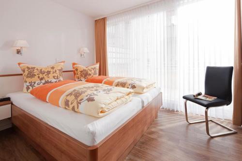 a bedroom with two beds and a chair and a window at Exquisit 3 in Norderney
