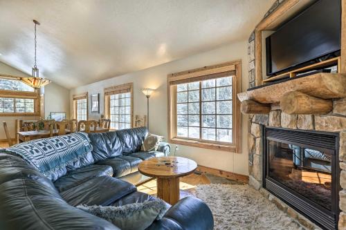 a living room with a leather couch and a fireplace at Mountainside Winter Park Ski Home with Hot Tub in Winter Park