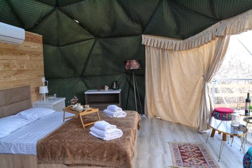 una camera da letto con una parete verde e asciugamani su un letto di Berkheva Glamping - ბერხევა გლემპინგი a Zemo Khodasheni