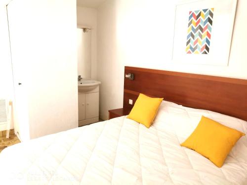 - une chambre avec un lit et 2 oreillers jaunes dans l'établissement Appartement 5 en duplex, avec deux chambres - LES SUITES DE ROBINSON - Résidence avec piscine en bord de Siagne, à Mandelieu-La-Napoule, à Mandelieu-la-Napoule
