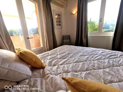 une chambre avec un lit avec des oreillers et une fenêtre dans l'établissement Appartement 5 en duplex, avec deux chambres - LES SUITES DE ROBINSON - Résidence avec piscine en bord de Siagne, à Mandelieu-La-Napoule, à Mandelieu-la-Napoule