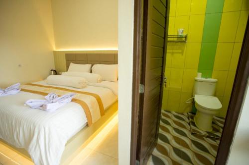 een slaapkamer met 2 bedden en een badkamer met een toilet bij HAYANA HOTEL in Taruna
