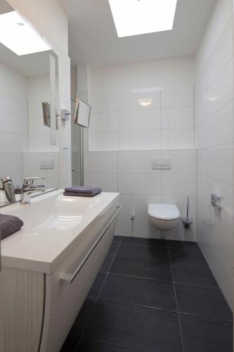 a white bathroom with a sink and a toilet at Exquisit 7 in Norderney