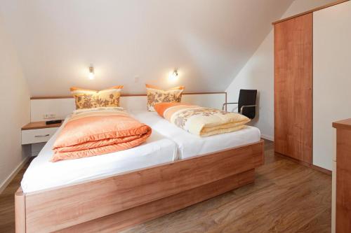 a bedroom with a bed with white sheets and orange pillows at Exquisit 8 in Norderney