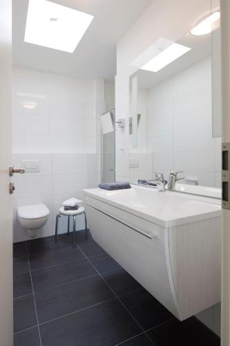 a white bathroom with a sink and a toilet at Exquisit 8 in Norderney