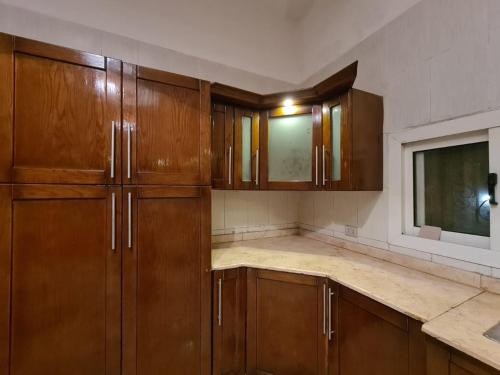 an empty kitchen with wooden cabinets and a tv at Especially villa with private entrance, garden and parking in Cairo