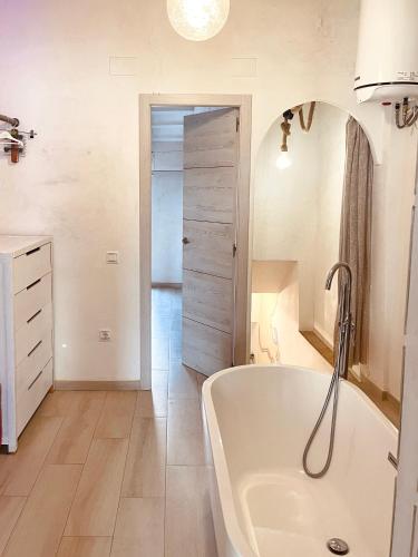 a white bathroom with a tub and a sink at El Nido: Una casita de ensueño in Deltebre