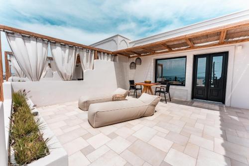 a patio with a couch and a table and chairs at IfestAu.4 Suites in Fira