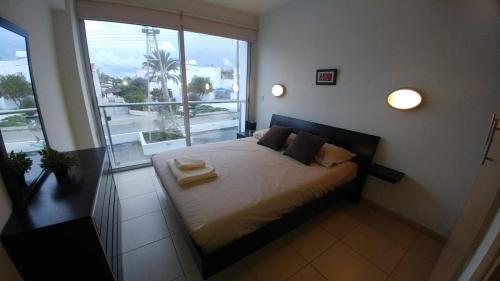 ein Schlafzimmer mit einem Bett und einem großen Fenster in der Unterkunft Coralli Spa Resort Protaras Stylish 1 Bedroom apartment in Protaras