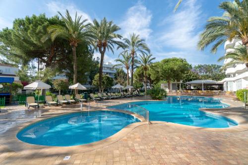 uma grande piscina com palmeiras num resort em Tropicana Hotel em Cala Millor