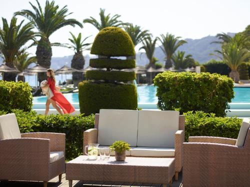 a woman in a red dress walking by a pool at The Ixian Grand & All Suites - Adults Only Hotel in Ixia