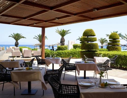 a restaurant with tables and chairs with the ocean in the background at The Ixian Grand & All Suites - Adults Only Hotel in Ixia