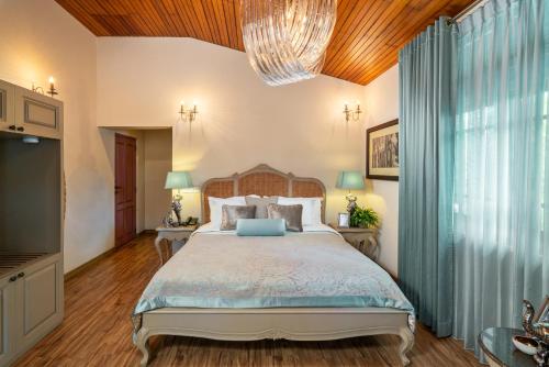 a bedroom with a large bed and a chandelier at Clove Villa in Kandy