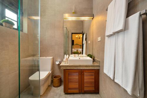 a bathroom with a sink and a toilet and a mirror at Clove Villa in Kandy