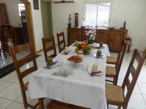 a table with a white table cloth and fruit on it at Le Quindio in Bras-Panon