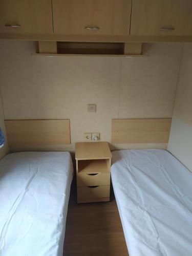 Cette petite chambre comprend deux lits et un bureau. dans l'établissement Camping le val du ternois, à Frévent