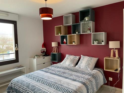 una camera da letto con una parete rossa, un letto e scaffali di Les Tuileries Eguisheim a Eguisheim