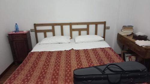 ein Schlafzimmer mit einem Bett mit einem Koffer drauf in der Unterkunft CASA DEL MAESTRO in Castel di Lama