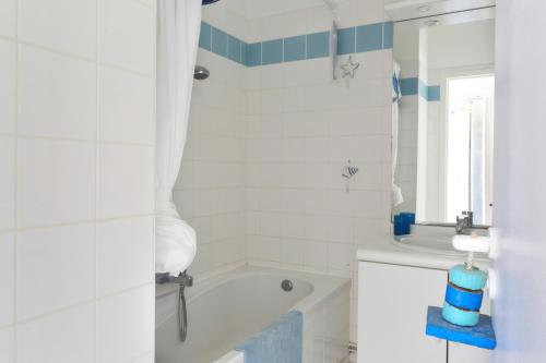 uma casa de banho branca com uma banheira e um lavatório em Ar Vro - Accès direct à la grande plage em Saint-Cast-le-Guildo