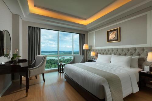 a bedroom with a bed and a desk and a window at Wyndham Panbil Batam in Batam Center