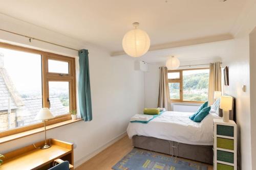 a bedroom with a bed and two windows at The Dormers - 5 BD Amazing Views of Stroud Valley 