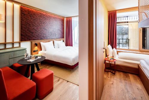 施伦斯Falkensteiner Family Hotel Montafon - The Leading Hotels of the World的一间有两张床和一把红椅子的酒店房间