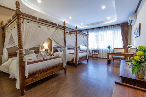 a bedroom with two canopy beds and a desk and a table at Bali Hotel in Phnom Penh