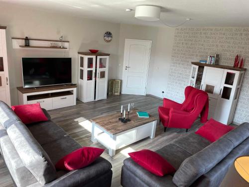 - un salon avec un canapé et des fauteuils rouges dans l'établissement Ferienwohnung an der Ems 75100, à Westoverledingen