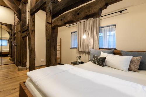 - une chambre avec un grand lit blanc et des poutres en bois dans l'établissement Biohotel WildLand Natural Resort, à Hornbostel