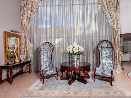 a living room with two chairs and a table with flowers at Bophirima Boutique Hotel in Rustenburg