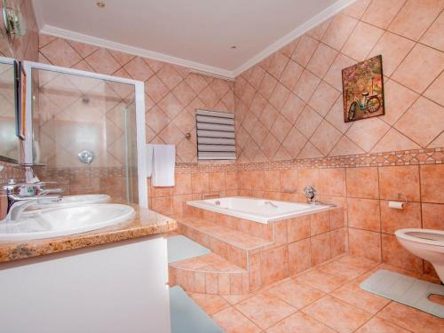 a bathroom with a tub and a sink and a toilet at Bophirima Boutique Hotel in Rustenburg