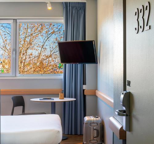 a room with a bed and a table and a tv at Ibis Budget Barcelona Viladecans in Viladecáns