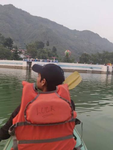 a man wearing a life vest in a boat in the water at The Periwinkle Homestay Bhimtal in Bhīm Tāl