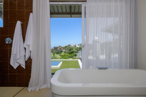 a bathroom with a white tub and a window at 11 on Fairway Beach Villa in Southbroom