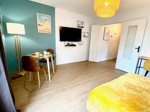 a bedroom with a bed and a table and a tv at Pluton - SILS in Caen
