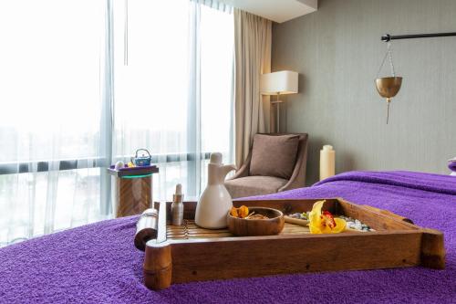 a bedroom with a purple bed with a tray of food on it at City of Dreams - Nobu Hotel Manila in Manila